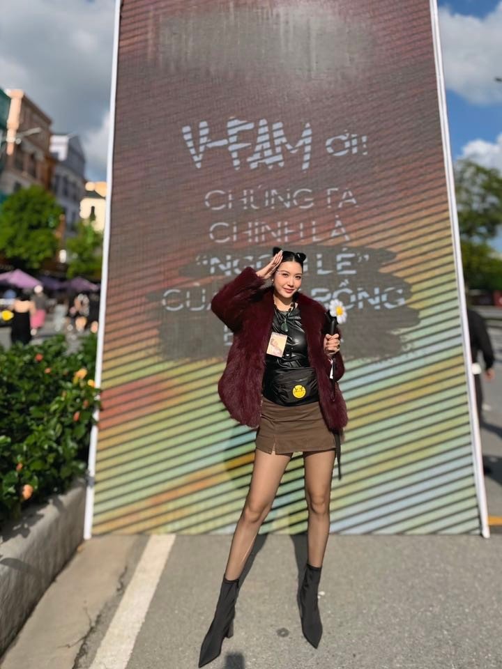 Á hậu Thúy Vân mặc áo khoác lông, cầm trên tay lighstick hoa cúc thiếu cánh của thần tượng.