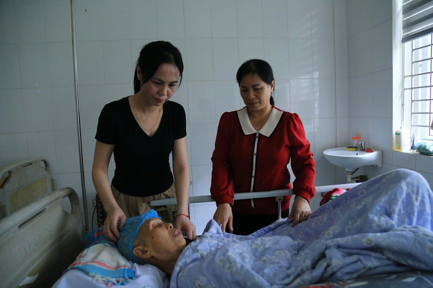 Chị Nguyễn Thị Mỹ (mặc áo đỏ) và em gái Nguyễn Thị Yến chăm sóc mẹ ở bệnh viện.