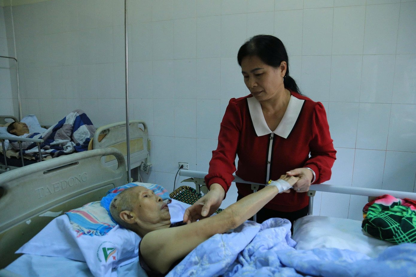 Chị Nguyễn Thị Mỹ (mặc áo đỏ) và em gái Nguyễn Thị Yến chăm sóc mẹ ở bệnh viện.