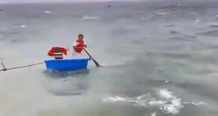 Hai người đàn ông chèo thuyền thúng ra biển cứu người nhưng bị sóng đánh trôi dạt đi xa.
