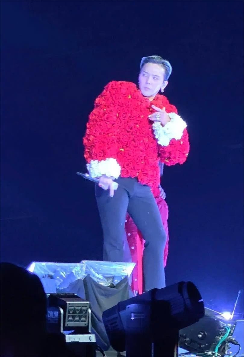 Điểm thú vị nhất trong loạt outfit lần này chính là việc G-Dragon mang lên sân khấu một bộ suit hoàn toàn mới gồm blazer và quần ống suông với tông trắng. Thay vì những bộ suit sequin quen thuộc như các sân khấu khác, lần này "anh Long" chọn phiên bản tối giản hơn với họa tiết kẻ sọc bắt sáng nhẹ, trông đúng chuẩn quý ông nhưng vẫn cực kì hợp vibe sân khấu.