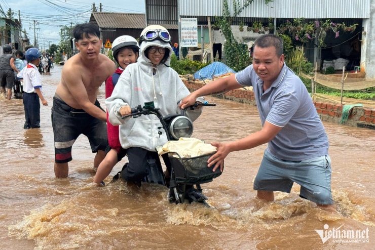 Nhiều phụ huynh phải dìu học sinh qua đoạn ngập.