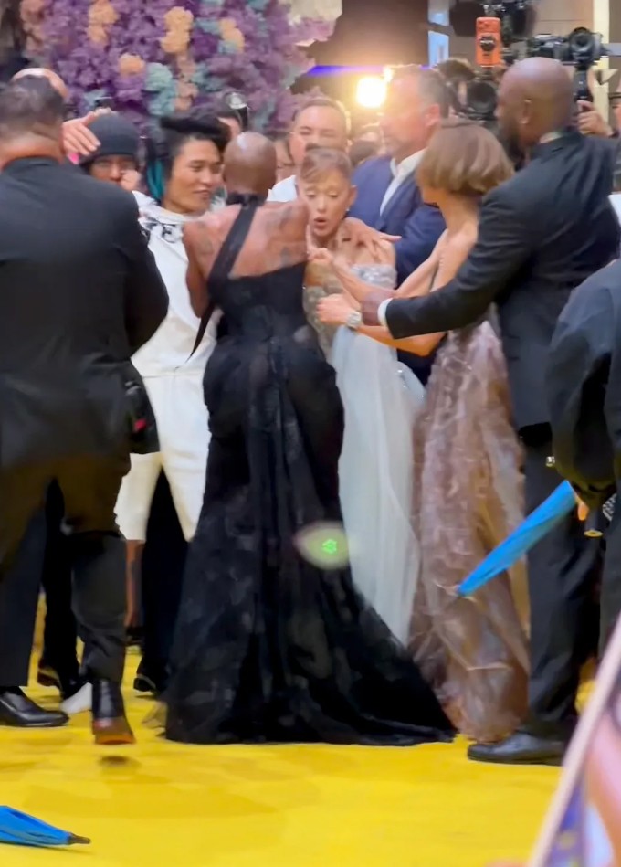 Cynthia Erivo (váy đen) lao vào giải cứu Ariana Grande khỏi fan cuồng (áo trắng).