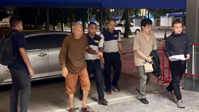 Cựu trụ trì Phra Ratchawisutthiprachanat (áo nâu) bị CIB dẫn giải. Ảnh: Nation