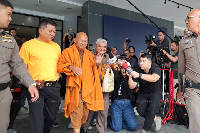 Cảnh sát hộ tống trụ trì Alongkot (ở giữa), hôm 27/8. Ảnh: Bangkok Post