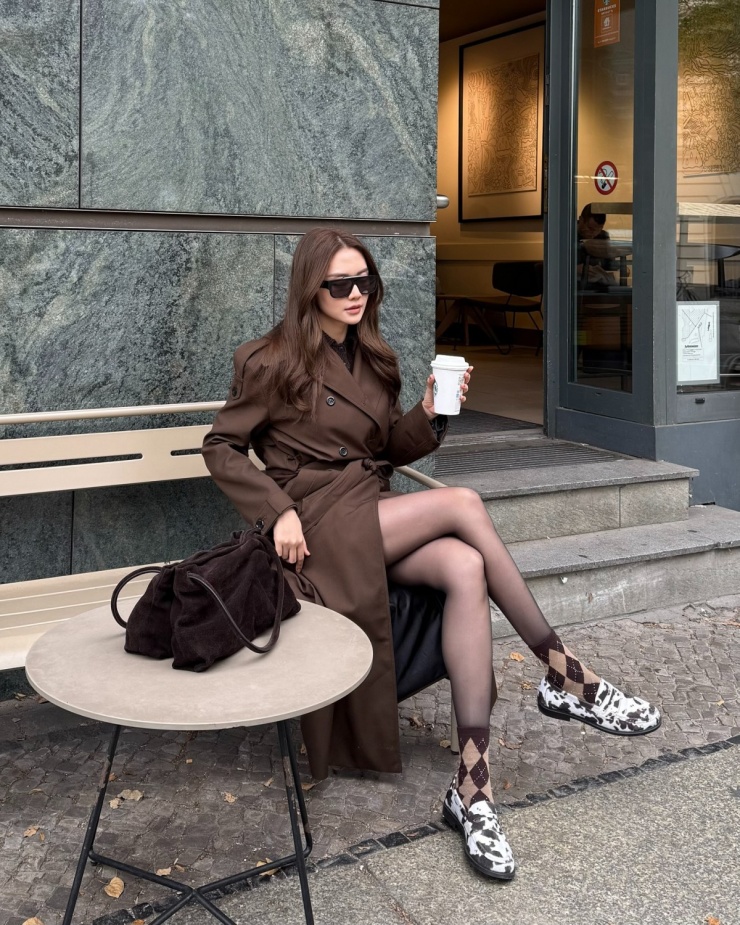 Thiều Bảo Trang bắt trend mốt nâu Mocha - xu hướng nổi bật mùa đông 2025. Ngoài chiếc trench coat sang chảnh, nữ ca sĩ còn phối loạt phụ kiện màu nâu như tất quả trám, túi xách da lộn.