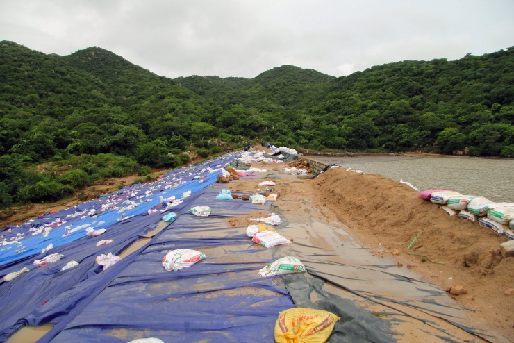 Đơn vị chuyên môn phủ bạt, đắp bao cát, gia cố tạm thời khu vực bị xói mòn, sạt lở. Ảnh: N.X