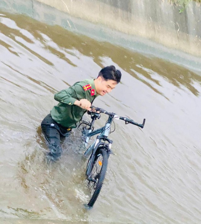 Thượng úy Hiệp hỗ trợ vớt chiếc xe đạp cháu bé đưa lên bờ. Ảnh: CAHT.