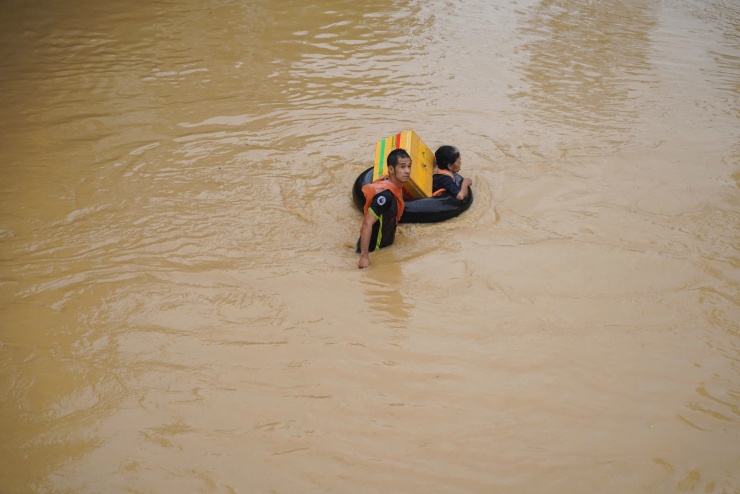 Người dân mang theo phao bơi, hoặc xăm ôtô tự chế, vừa bám theo dải dây được lực lượng chức năng đánh dấu để đến nơi an toàn.