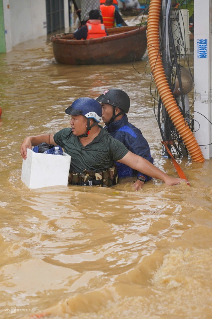 Một số người dùng thùng xốp, phao tự chế luồn lách bên những trụ điện để thoát ngập. Hai ngày nay, khu vực này mất điện do mưa lớn, lũ dâng cao.