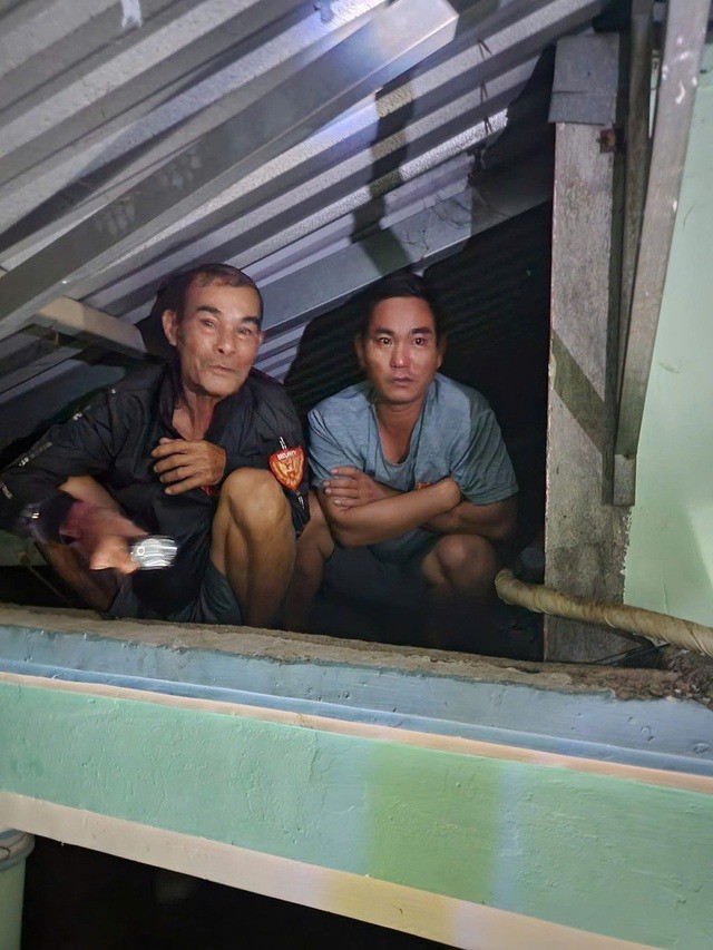 Gia đình có người già và trẻ nhỏ đang ngồi trên mái nhà ở thôn Thủy Tú, phường Tây Nha Trang