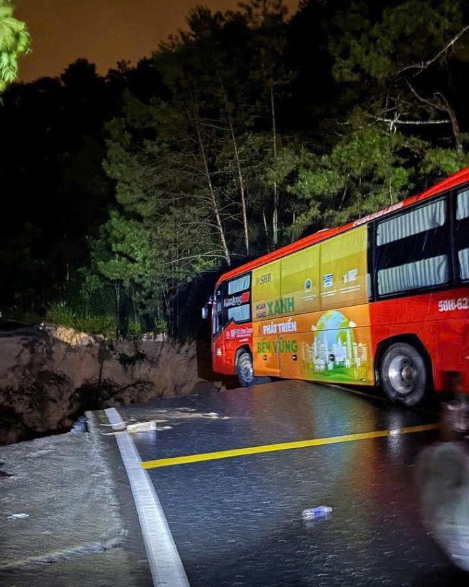 Ôtô khách nằm mấp mé hố sâu sau sạt lở đèo. Ảnh: Người dân cung cấp