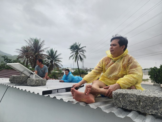 Người dân phường Nam Nha Trang ngồi trên mái nhà chờ cứu hộ, sáng 20/11. Ảnh: Bảo Hòa