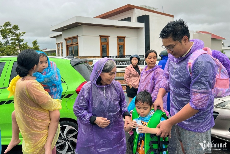 Gia đình anh Võ Đình Trí được giải cứu sau nhiều giờ bị cô lập trong lũ. Ảnh: Xuân Ngọc