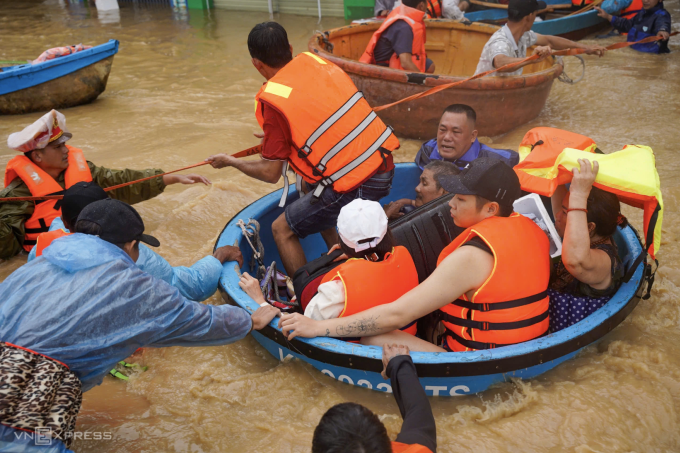 Các đội cứu hộ phường Tây Nha Trang, Khánh Hòa dùng thuyền thúng chở người, tài sản đến nơi an toàn. Nước lũ chảy xiết trên đường khiến việc cứu hộ gặp khó khăn. Ảnh: Bùi Toàn