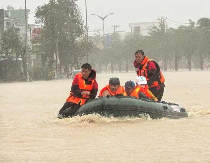 Các thành viên trong đội cứu hộ SOS 38 Hà Tĩnh đưa người dân bị cô lập trong nước lũ tại phường Quy Nhơn Bắc, Gia Lai đến nơi an toàn, ngày 19/11. Ảnh: Lương Vĩnh Long Nhật