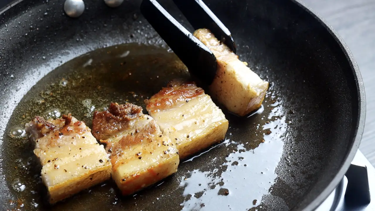 Làm nóng chảo trên lửa vừa, cho 1 muỗng cà phê dầu ăn. Đặt miếng thịt ba chỉ vào, áp chảo đến khi hai mặt vàng đều. Dùng kéo cắt thịt thành từng miếng vừa ăn, tiếp tục áp chảo các cạnh cho lên màu đẹp, sau đó gắp ra để riêng.