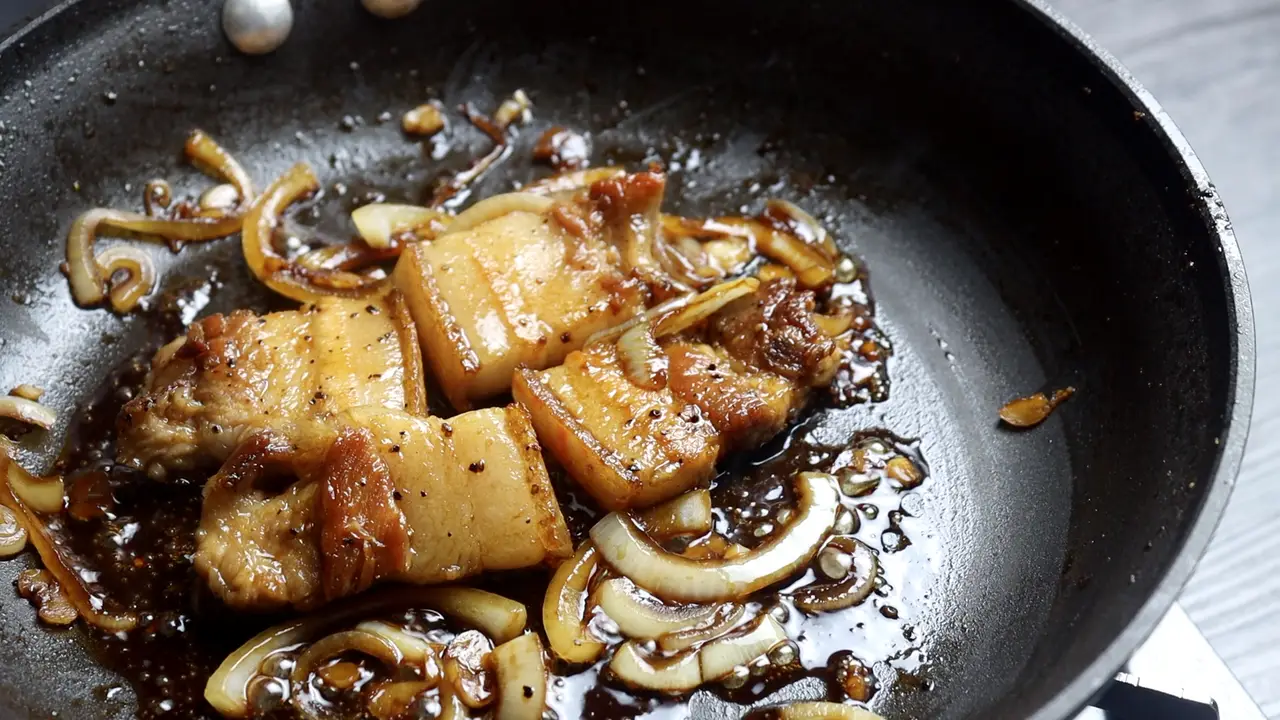 Trút bỏ bớt phần mỡ thừa trong chảo. Cho tỏi băm và hành tây vào, xào đến khi hành mềm và thơm. Cho thịt ba chỉ đã áp chảo vào trở lại. Đổ phần nước sốt vào, đảo đều và rim đến khi hơi sệt lại thì tắt bếp.