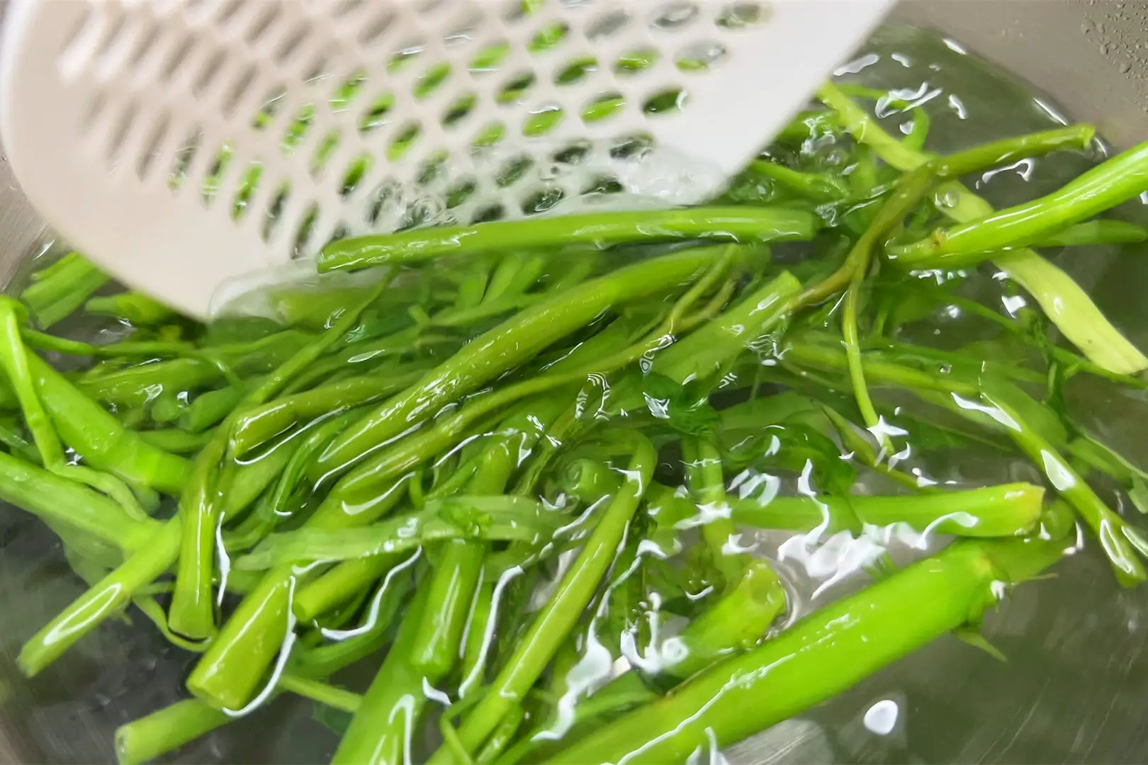 Ngâm nước lạnh để rau hạ nhiệt nhanh, nhờ vậy giữ được độ giòn và màu xanh tươi. Sau đó, rắc sẵn một chút muối và bột ngọt vào phần rau muống đã ráo nước.