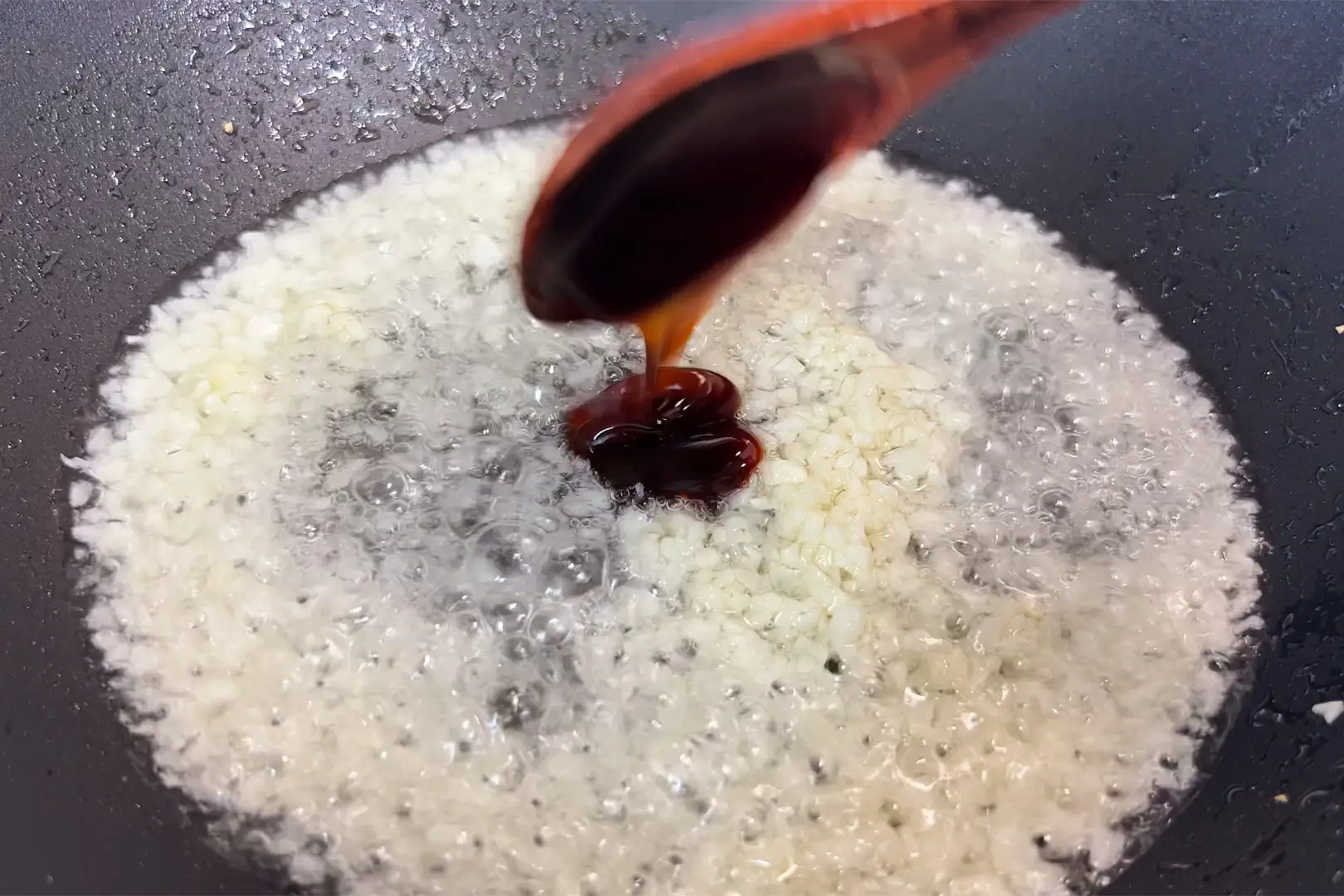 Làm nóng chảo, cho dầu ăn rồi phi thơm tỏi. Thêm 1 muỗng dầu hào và đảo đều cho thơm.