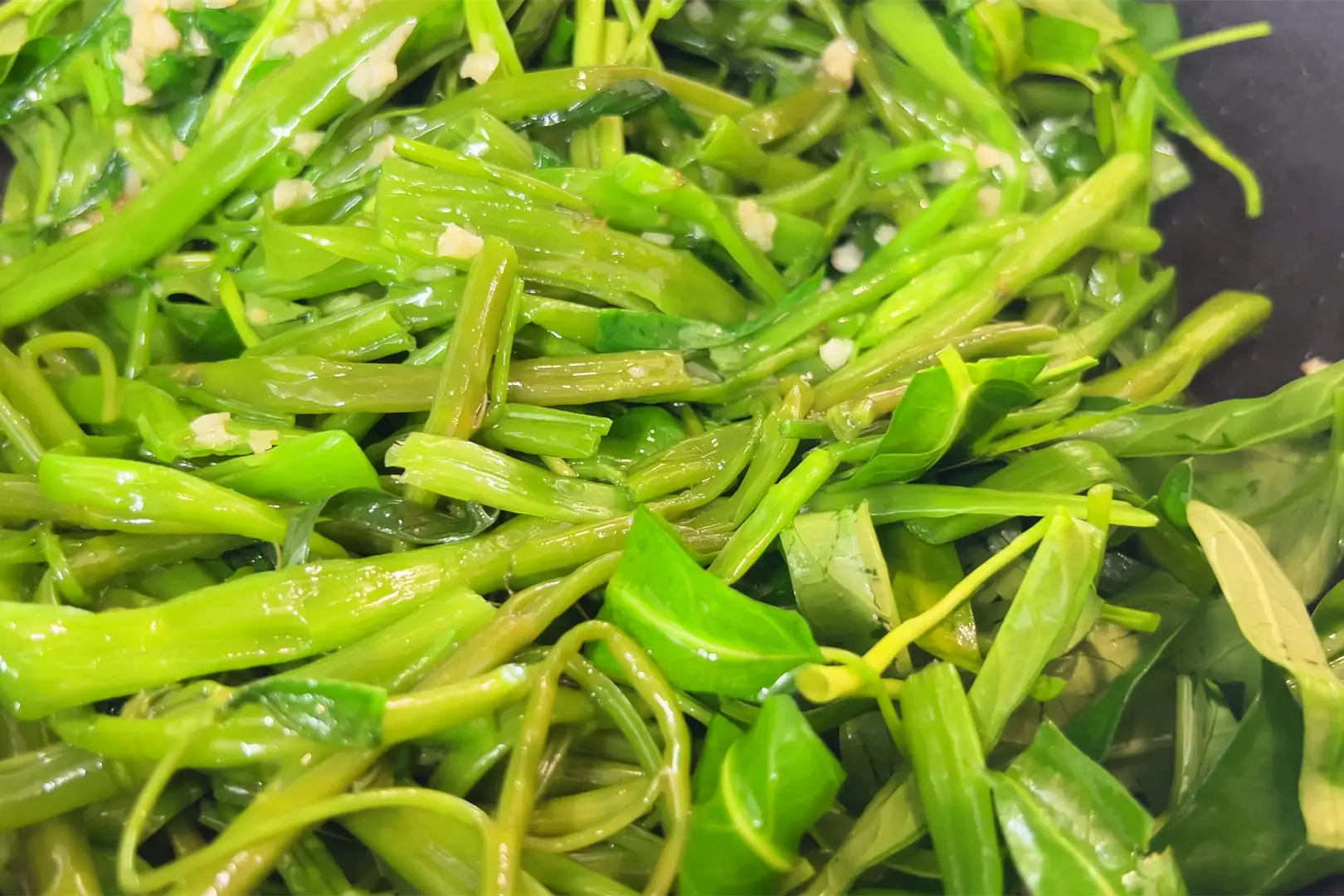 Cho toàn bộ rau muống vào chảo, mở lửa to và đảo nhanh khoảng 40 giây đến khi lá vừa mềm thì tắt bếp, cho ra đĩa.