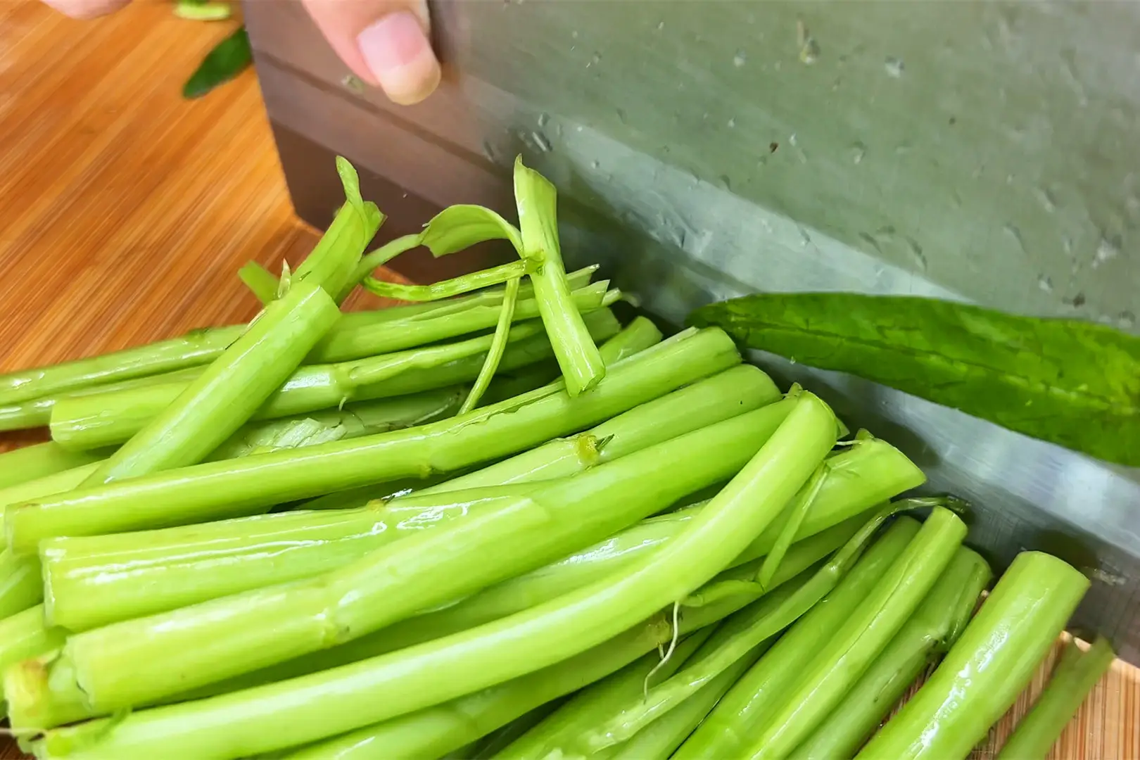 Rau muống cắt bỏ phần gốc già, loại bỏ lá úa. Rửa sạch rồi dùng sống dao đập nhẹ phần thân trước khi cắt khúc. Phần thân và lá để riêng. Tỏi bóc vỏ và băm nhỏ.