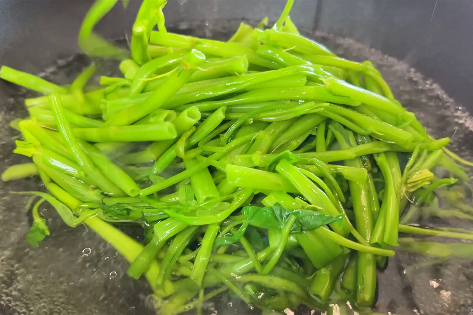 Đun sôi nước, cho vào 1 muỗng muối và 1 muỗng dầu ăn, sau đó cho phần thân rau vào chần 5–10 giây rồi vớt ra ngay.