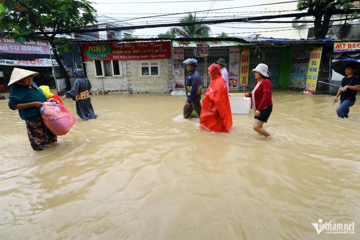 Người dân lội qua điểm ngập để về nhà sau những ngày sơ tán vì lũ lớn. Ảnh: Xuân Ngọc