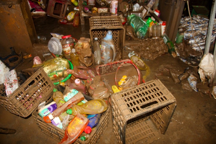 Đối diện quán bà Liên, cửa hàng tạp hóa của bà Kim Ngân (41 tuổi) cũng bị lũ cuốn nhiều hàng hóa. Sáng nay, bà Ngân lội bùn nhặt từng gói bánh, chai nước mắm, dầu ăn… để vớt vát thiệt hại.