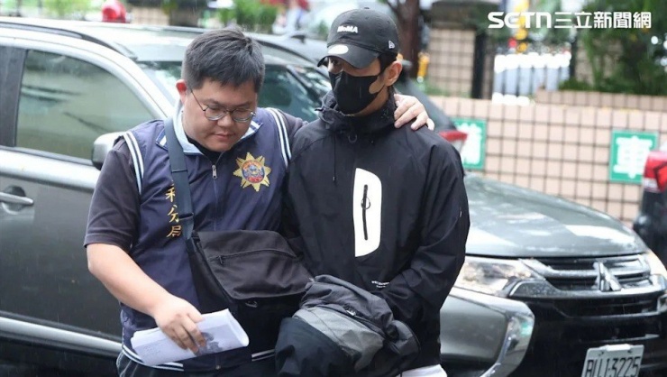 Kiệt Khải bị còng tay và áp giải đến Viện kiểm sát do liên quan vụ trốn nghĩa vụ.