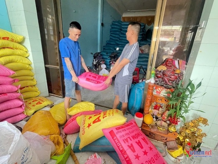 Nhân viên cửa hàng đang khuân những bao gạo bị ngập nước ra ngoài. Ảnh Trần Hoàn