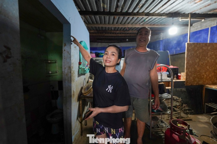 Chị Thuý Liễu đứng cạnh vạch nước cao quá đầu người trên tường nhà. “Lúc đó chỉ kịp chạy giữ mạng. Giờ mong nhất có nước sạch và lương thực để cầm cự vài ngày tới”, chị nói.