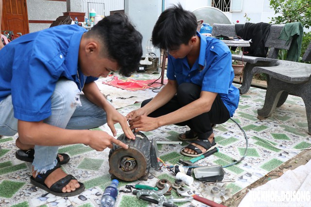 Hai sinh viên Trường Cao đẳng Công nghệ - Năng lượng Khánh Hòa tỉ mỉ sửa máy bơm bị hư do ngập nước lũ. Ảnh: Duy Ngọc