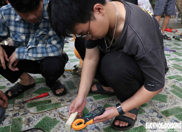 Sinh viên Nguyễn Thanh Tùng cẩn thận kiểm tra cường độ dòng điện của một chiếc tủ lạnh sau khi khắc phục. Ảnh: Duy Ngọc