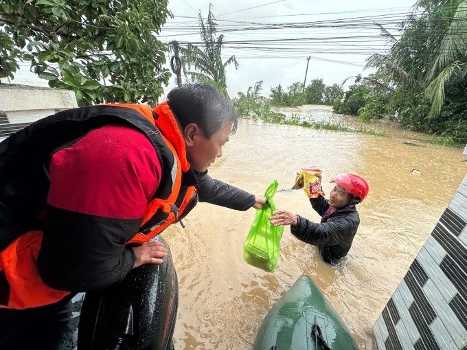 Một người dân ở phường Tuy Hòa, Đăk Lăk lội nước lũ ra nhận đồ cứu trợ của các đội từ thiện, chiều 21/11. Ảnh: Lương Vĩnh Long Nhật