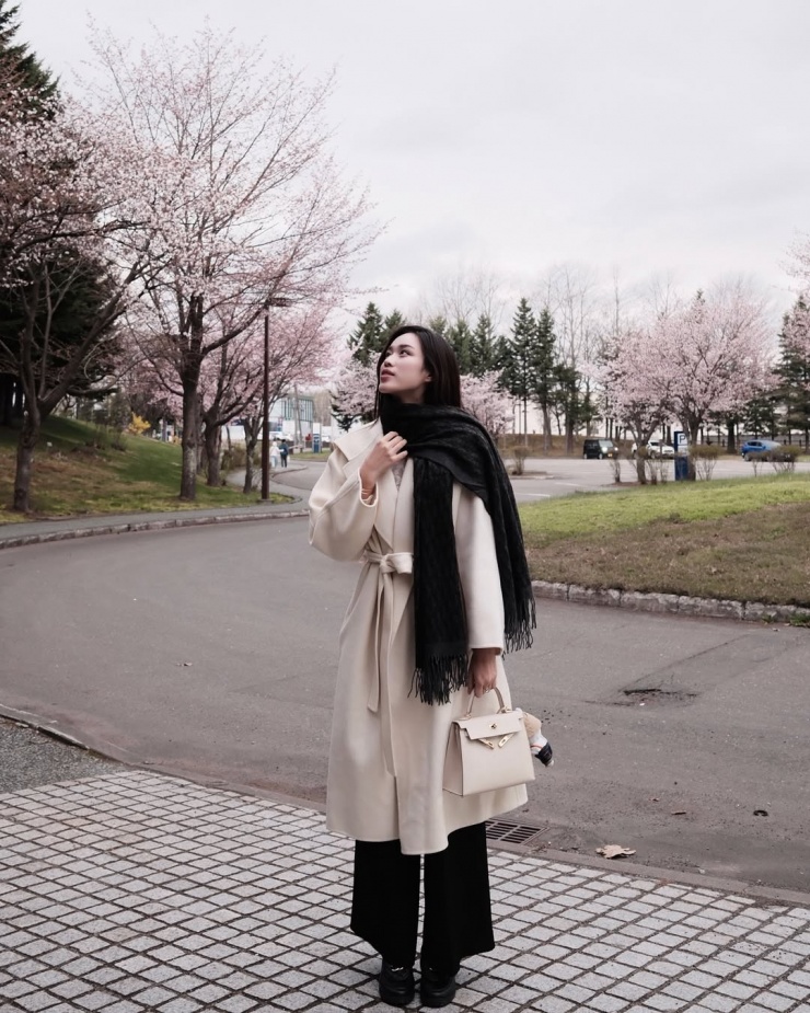 Trench coat - thiết kế kinh điển của thế giới - cũng có mặt trong tủ đồ của nhiều người nổi tiếng. Hoa hậu Đỗ Thị Hà dạo phố với áo khoác màu kem đồng điệu túi Kelly mini. Cô chọn quần ống suông và giày loafer.