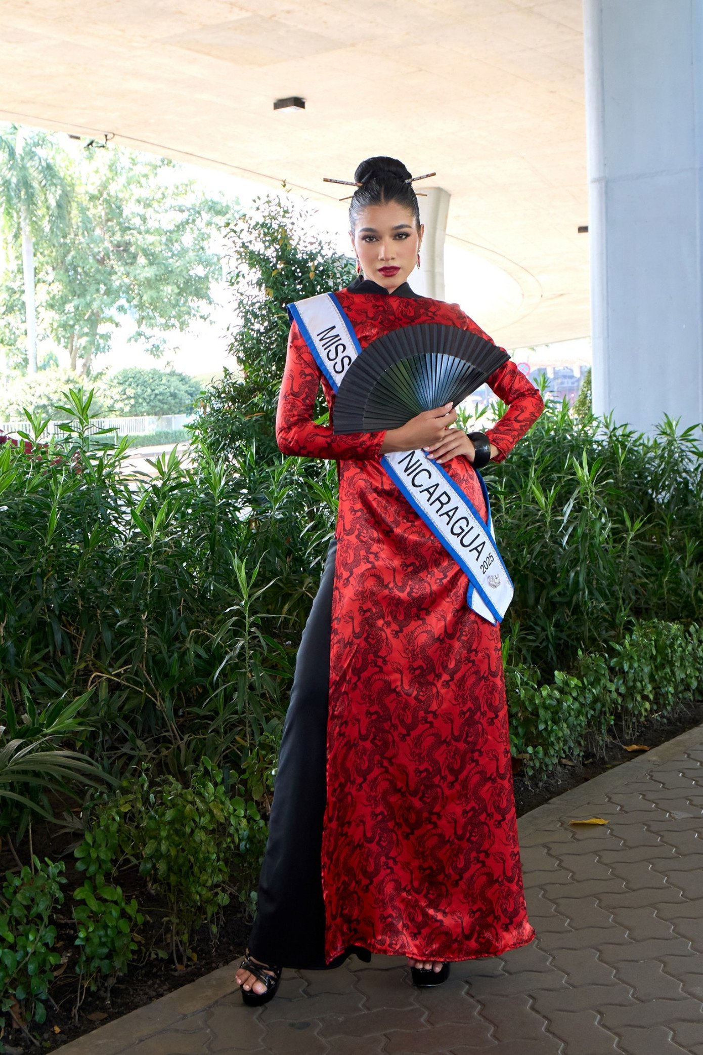 Miss Cosmo Nicaragua 2025 Marian Rodríguez cũng nhận được sự cổ vũ nồng nhiệt khi tự tin catwalk tại sảnh sân bay trong tà áo dài đỏ rực rỡ, kết hợp kiểu tóc búi cao thanh lịch.