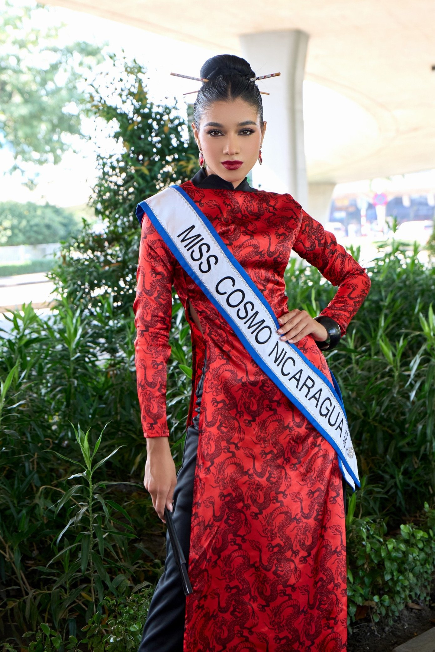 Miss Cosmo Nicaragua 2025 Marian Rodríguez cũng nhận được sự cổ vũ nồng nhiệt khi tự tin catwalk tại sảnh sân bay trong tà áo dài đỏ rực rỡ, kết hợp kiểu tóc búi cao thanh lịch.