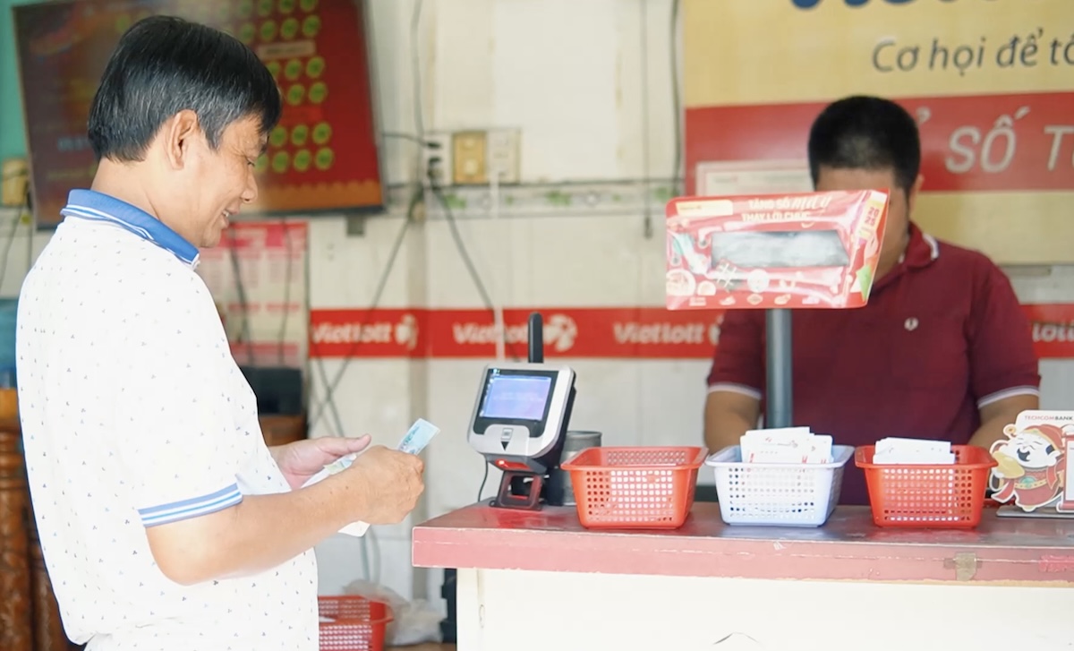 Ông Hoàng Linh (áo trắng) đang mua vé số tại điểm bán hàng của anh Vinh.