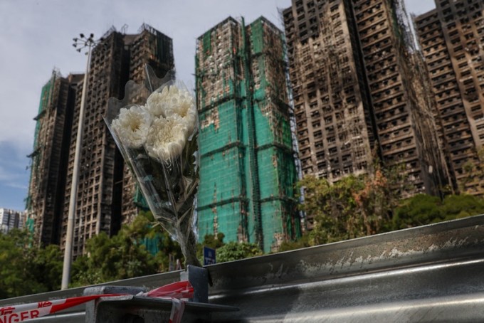 Người dân Hong Kong đặt cúc trắng trước cụm chung cư Wang Fuk Court để tưởng niệm các nạn nhân. Ảnh: AP