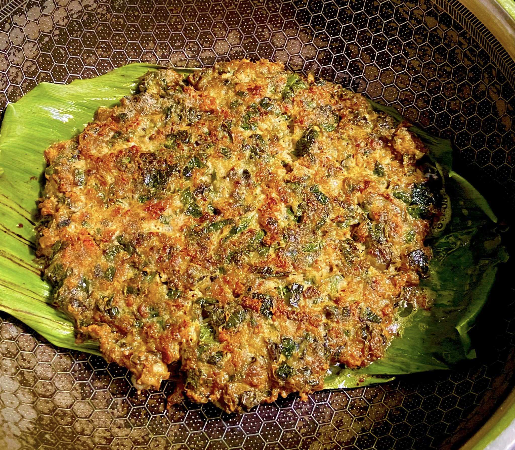 Lót 1 lớp lá chuối xuống đáy chảo, trải đều phần chả ốc lên trên mặt lá chuối. Dùng 1 chiếc lá chuối nữa đặt lên mặt trên. Dùng mức nhiệt hoặc lửa nhỏ nhất để áp chảo chín đều 2 mặt chả.