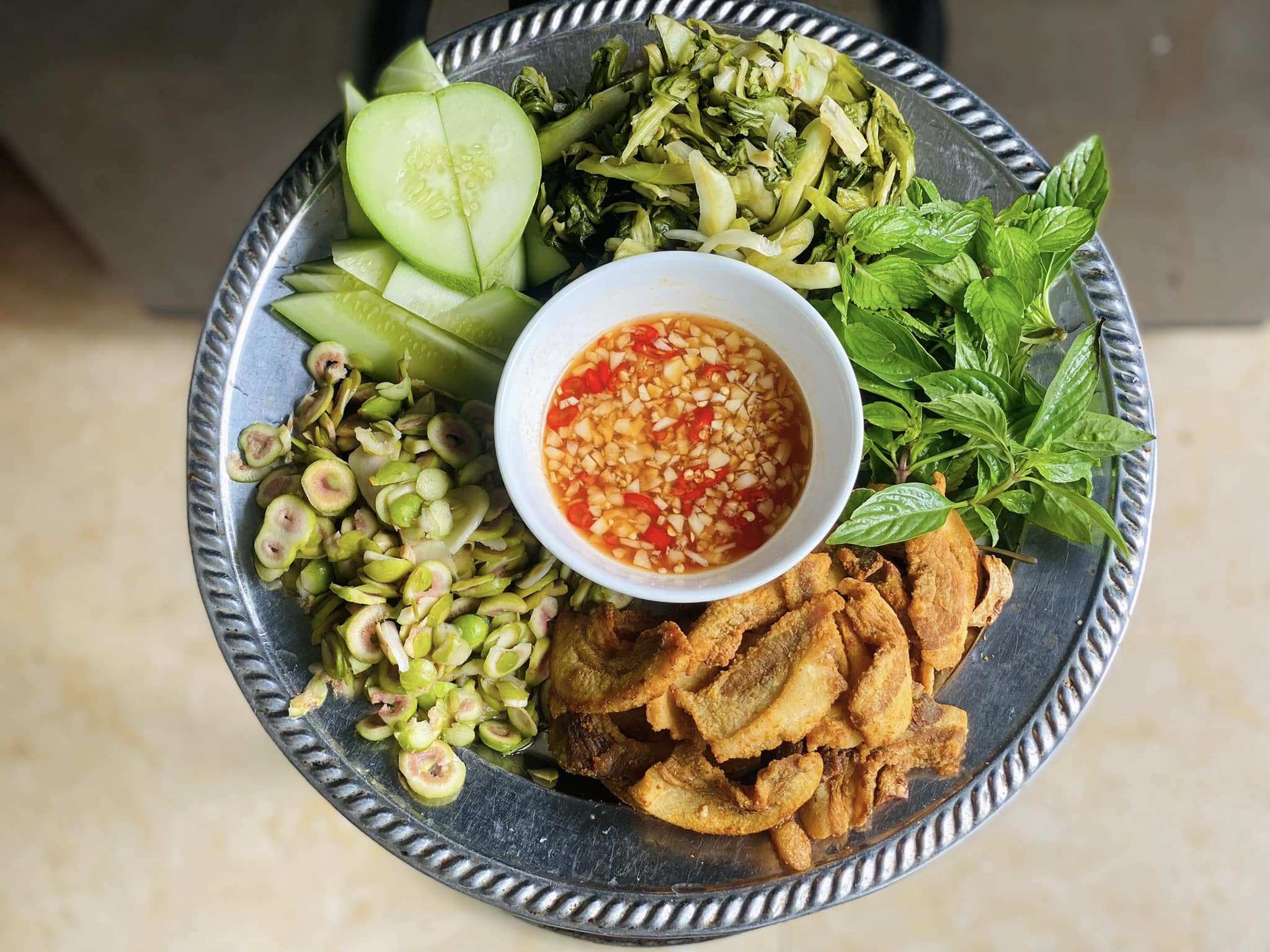 Tóp mỡ ăn kèm dưa muối, sung muối, dưa chuột cùng rau thơm, chấm nước mắm chua ngọt ngon hết xảy.