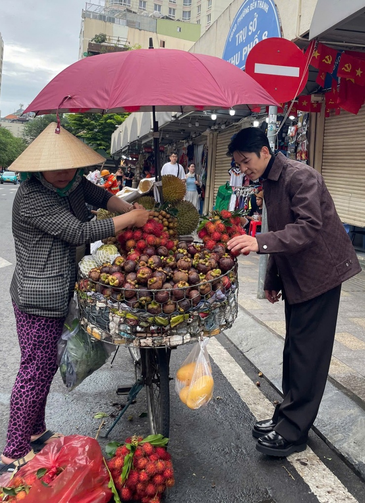 Lâm Bách Hoành mua trái cây của một người bán rong trước chợ Bến Thành.