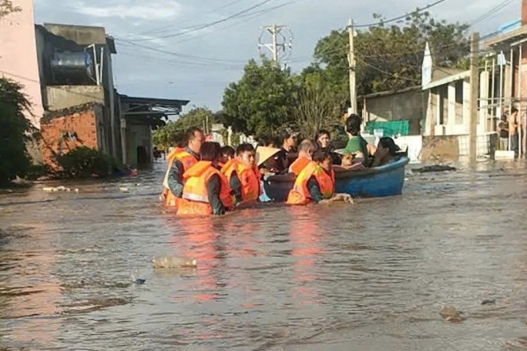Lực lượng chức năng ngâm mình trong nước hỗ trợ di dời người dân.