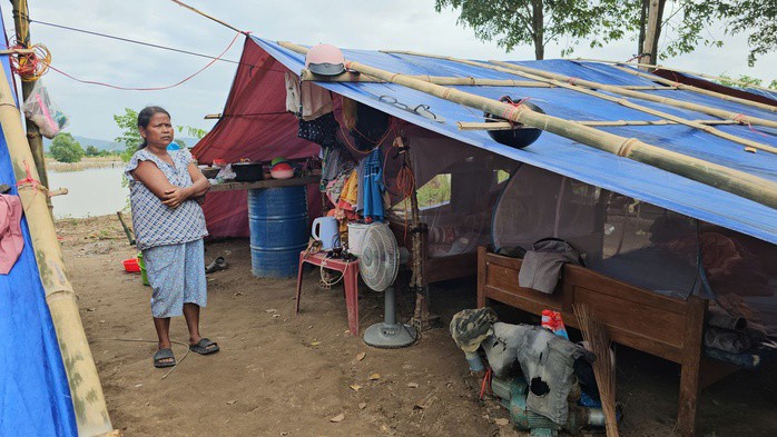 Bà Rơ Ô Loan cùng con cháu dựng lều ở tạm trên bãi đất trống gần ngôi nhà bị ngập