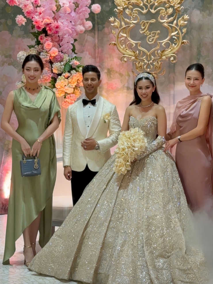 Lương Thùy Linh mặc đầm lụa cổ đổ của một local brand Việt Nam, kết hợp loạt phụ kiện, trang sức trị giá hơn một tỷ đồng khi dự đám cưới của Tiên Nguyễn. Thiết kế của hoa hậu có tông màu xanh olive, kiểu dáng bất đối xứng, tạo điểm nhấn một bên vai.