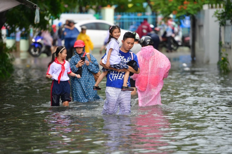 Trên đường Hoàng Hoa Thám, nhiều học sinh, phụ huynh bì bõm lội nước. Anh Phạm Trung Kiên, cõng con đi học về, cho biết lần đầu thấy mưa khiến đường ngập sâu. “Nhà gần nên tôi cõng con về cho an toàn”, anh Kiên nói.