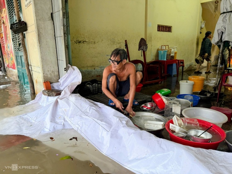 Ông Thái Quang Hậu, 58 tuổi, nhà ở đường Hoàng Hoa Thám dùng bạt chắn ngăn nước tràn vào nhà. Ông cho biết mưa lớn kết hợp triều cường nên nơi này bị ngập nặng. .