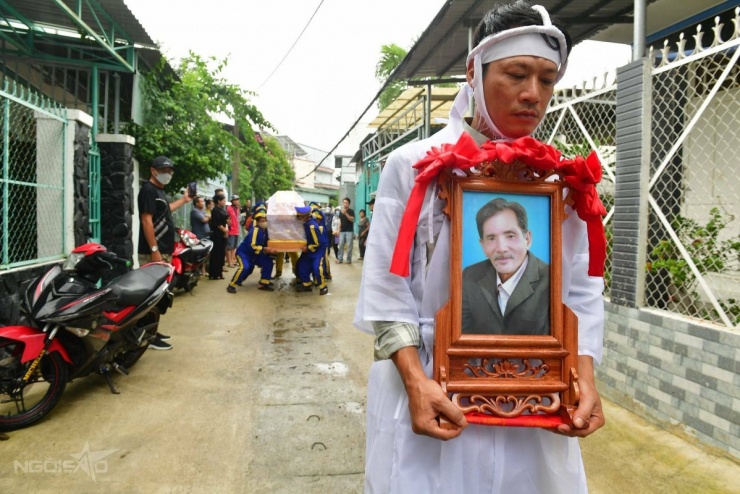 Thanh Tùng, 47 tuổi, ôm di ảnh bố, gương mặt lộ vẻ mệt mỏi sau hai ngày lo hậu sự cho ông.