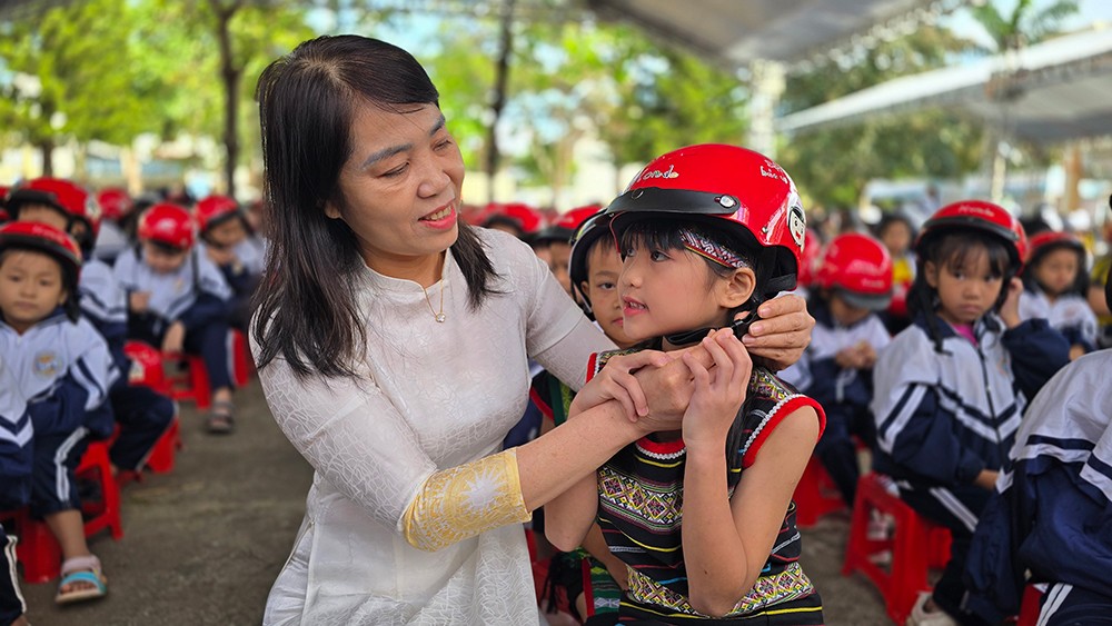 Giáo viên hướng dẫn các em đội mũ bảo hiểm đúng cách